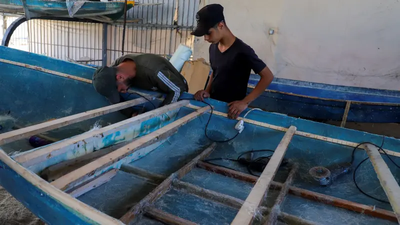 صور - الغزيون يصلحون زوارق الصيد من إطارات الأبواب القديمة
